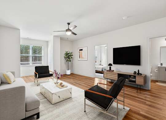 A living room with a grey couch, a white coffee table, a black chair, and a TV.