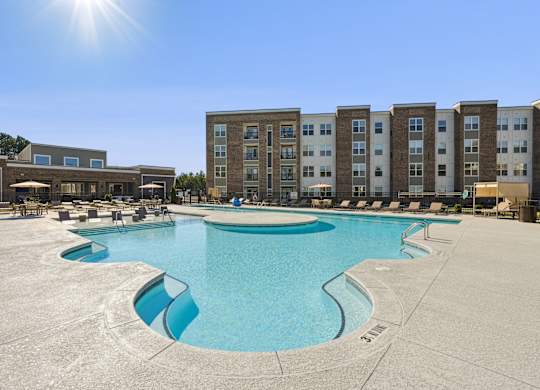 A large swimming pool in front of apartment buildings on a sunny day.