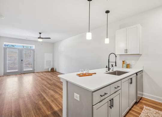 A kitchen with a white countertop and wooden floors.