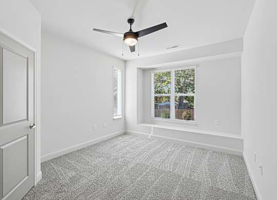 A room with a ceiling fan and a window with blinds.