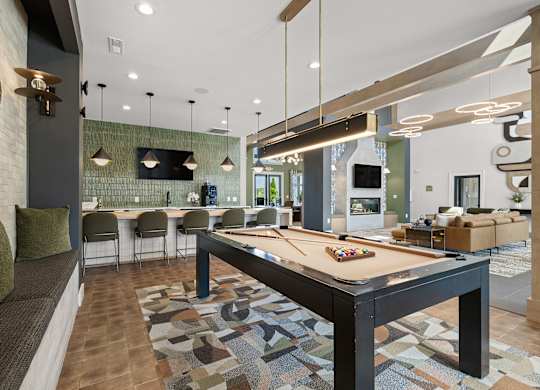 A billiard table is in the middle of a room with a couch and chairs.