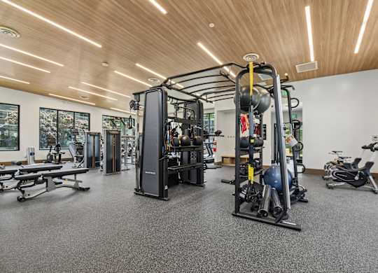 A gym with a variety of equipment including a weight machine, a bench press, and a rowing machine.