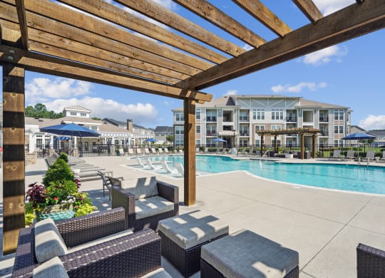 a large swimming pool with lounge chairs and a wooden pergola