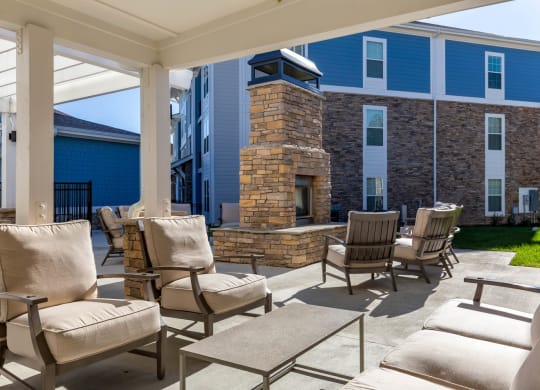 covered patio with chairs and a fireplace