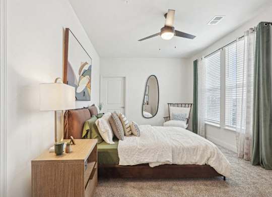 A bedroom with a bed, nightstand, and a ceiling fan.