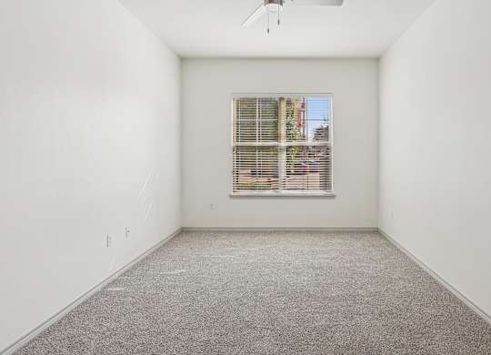 A room with a window and a ceiling fan.