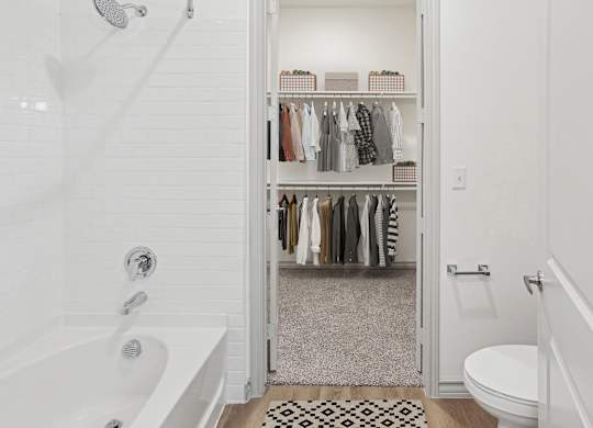 A white bathroom with a walk in closet.