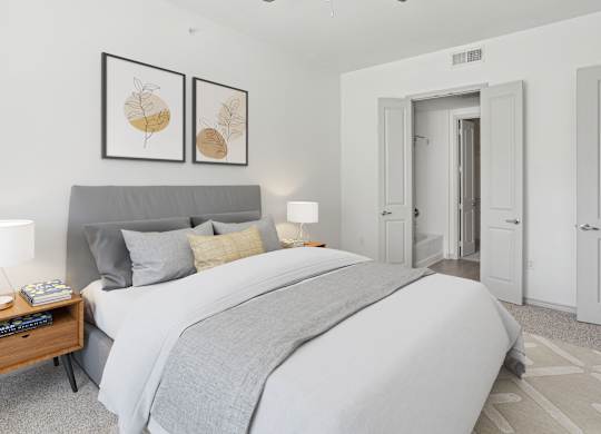 A bedroom with a large bed and two framed pictures on the wall.