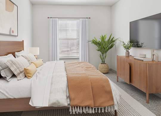 A bedroom with a bed, a TV, and a plant.