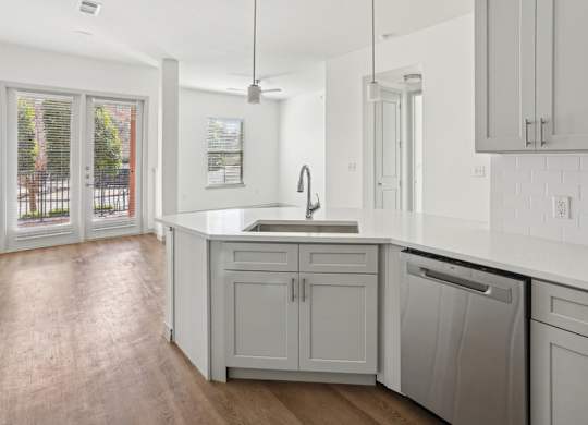 A kitchen with white cabinets and a wooden floor.