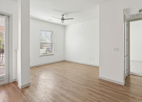 A room with a ceiling fan and a window with blinds.