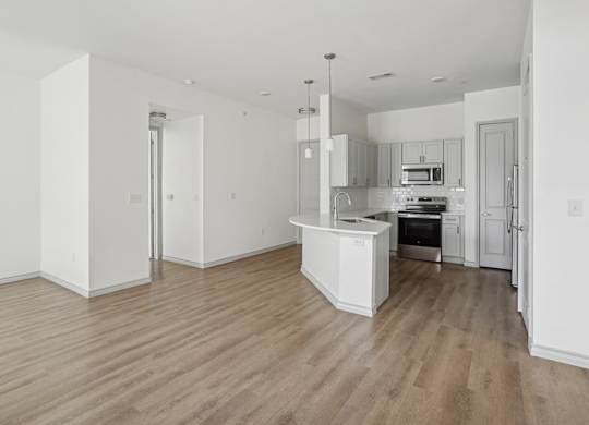 A kitchen with white cabinets and a wooden floor.