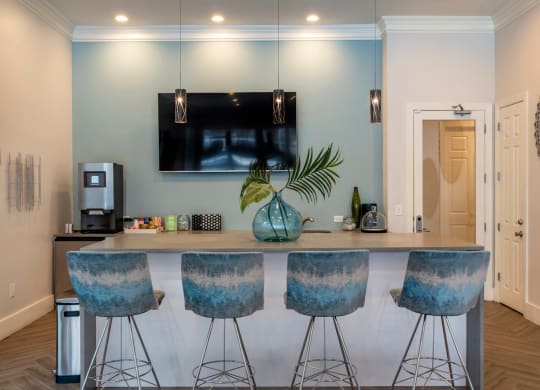a kitchen with a bar with four stools and a tv on the wall