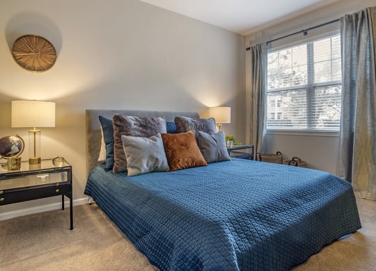 the master bedroom has a large window and a blue bed with pillows