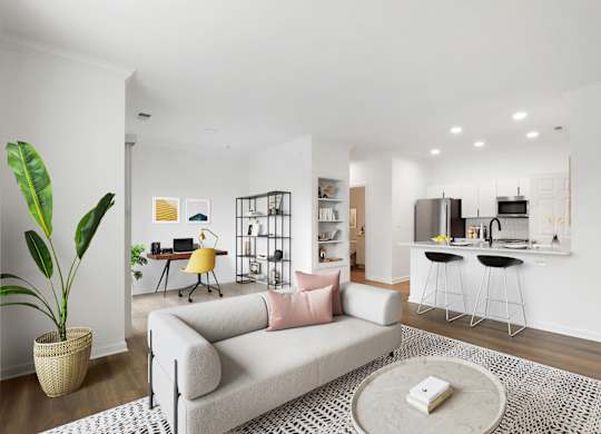 A living room with a grey couch, a coffee table, and a potted plant.