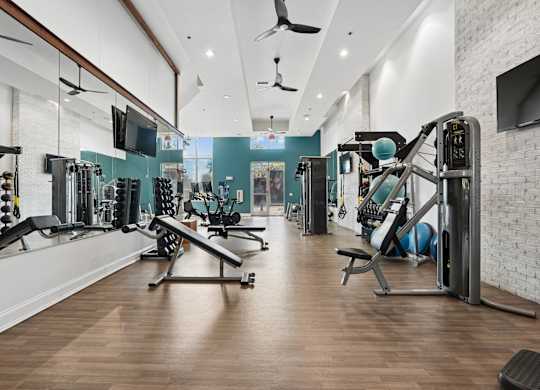 A gym with a variety of equipment including treadmills, weights, and exercise machines.