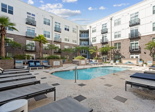 a swimming pool with lounge chairs in front of an apartment building