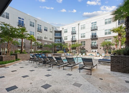 a courtyard with a pool and lounge chairs in front of apartment buildings
