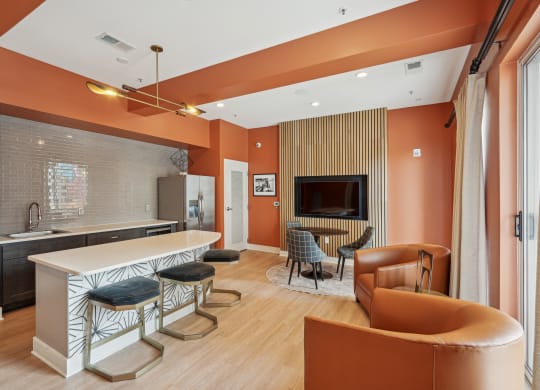a living room with orange walls and a kitchen with a table and chairs