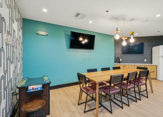 a dining room with a wooden table and chairs and a blue wall with a television