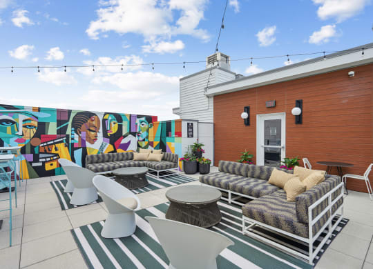 a patio with couches and chairs and a mural on the wall
