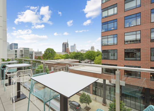 a rooftop patio with tables and chairs and a city in the background