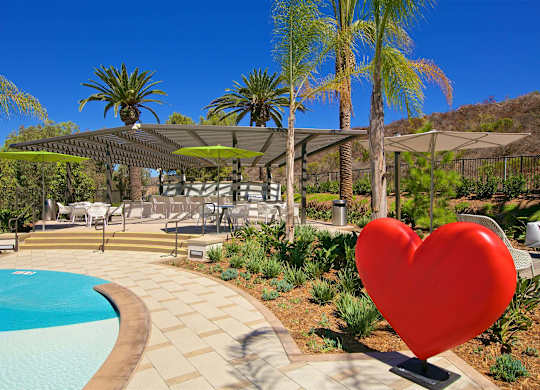 Pool deck with red heart sculpture and pergola at Casa Mira View Apartments, San Diego, CA