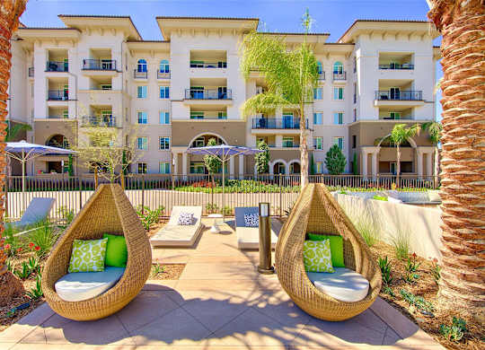 Outdoor lounge area with wicker pod chairs at Casa Mira View Apartments, San Diego, California