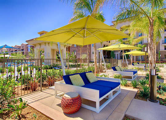 Poolside daybeds with yellow umbrellas and blue cushions at Casa Mira View Apartments, San Diego, California