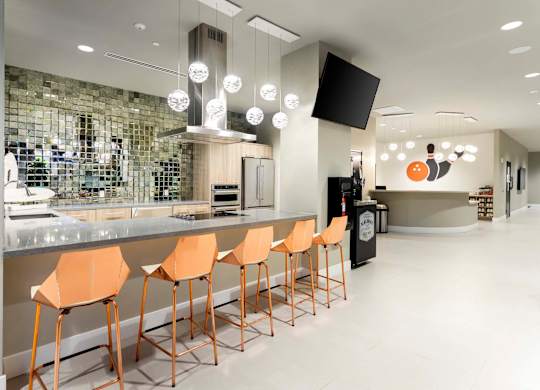 Community kitchen with bar seating and pendant lights at Elements Apartments, Irvine, CA 92612