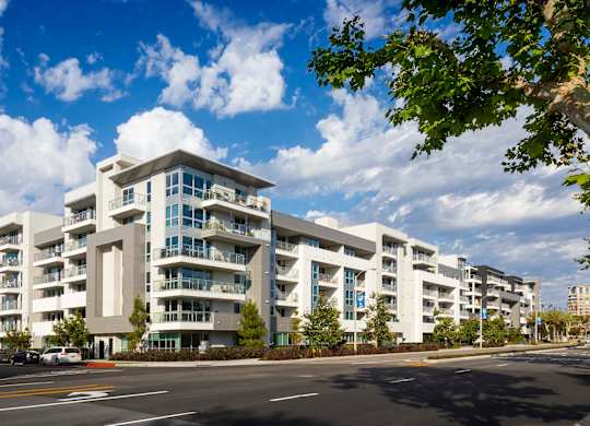 Modern white apartment building with balconies and street view at Elements Apartments, Irvine, 92612