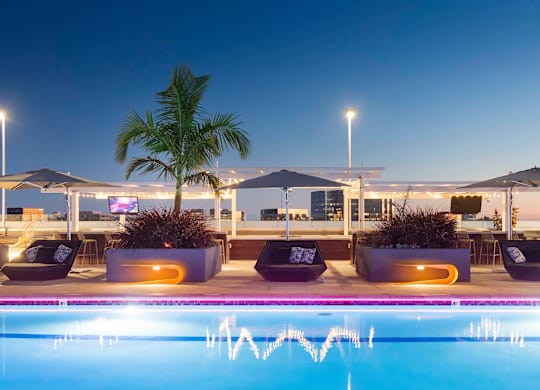 Poolside lounge area with daybeds and evening lighting at Elements Apartments, Irvine, California