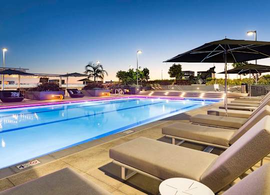 Rooftop pool deck at twilight with illuminated water at Elements Apartments, Irvine
