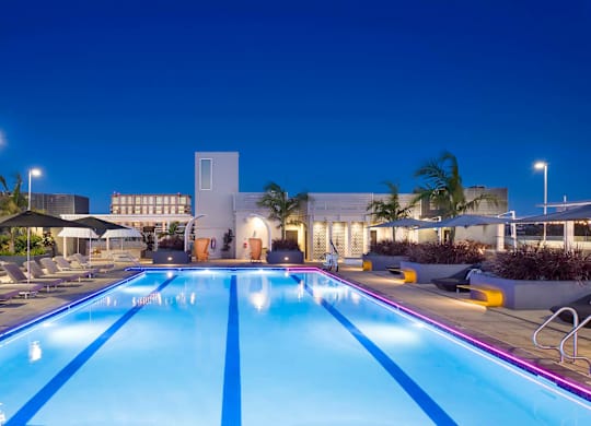 Resort style lap pool with illuminated deck at twilight at Elements Apartments, California, 92612