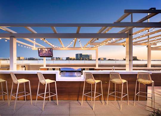 Rooftop bar with waterfront views and string lights at Elements Apartments, Irvine, CA 92612