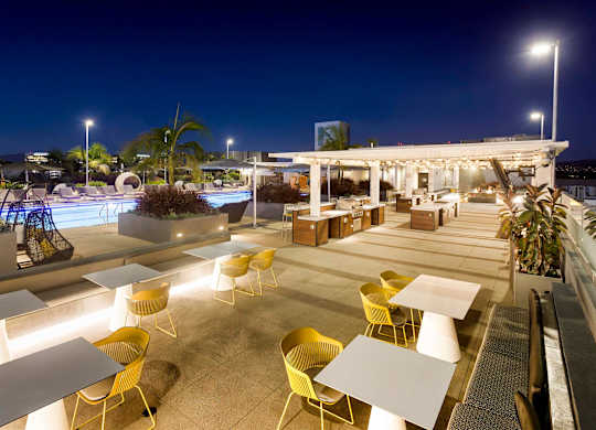 Outdoor dining terrace with pool and covered seating at Elements Apartments, Irvine, California