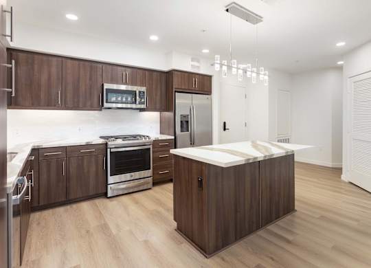 Kitchen with island stainless appliances and modern chandelier at Elements Apartments, Irvine, California