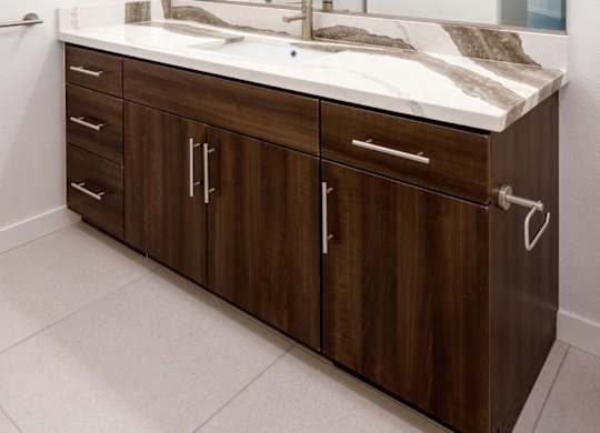 Double vanity bathroom with marble countertop and wood cabinetry at Elements Apartments, Irvine, 92612