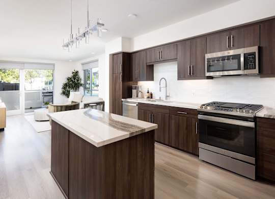 Open concept kitchen with island and patio access at Elements Apartments, California