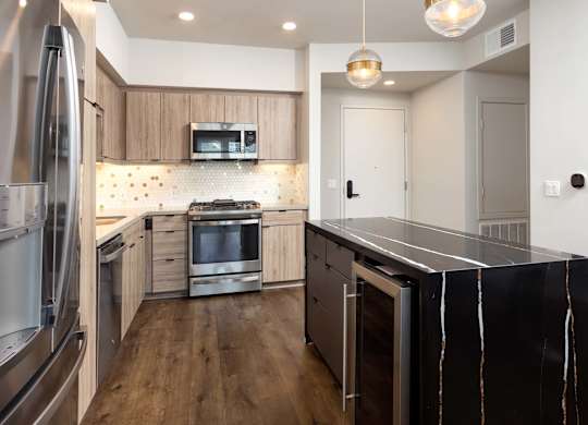 Modern kitchen with dark waterfall island and wood cabinets at Elements Apartments, Irvine, CA