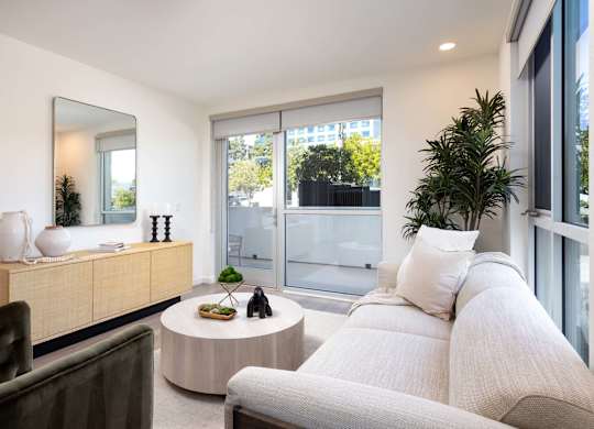 Living room with neutral sofa and sliding glass door at Elements Apartments, Irvine, CA