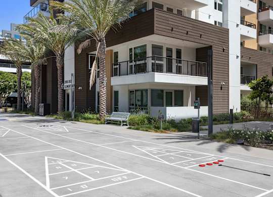 Shuffleboard court with parking and residential buildings at Elements Apartments, Irvine