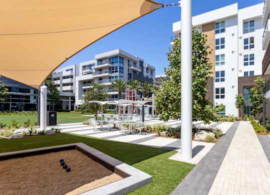 Courtyard with bocce ball court and shaded seating areas at Elements Apartments, Irvine, California