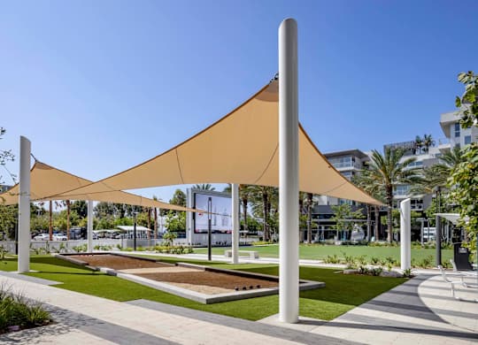 Outdoor recreation lawn with shade canopies and bocce courts at Elements Apartments, Irvine, California