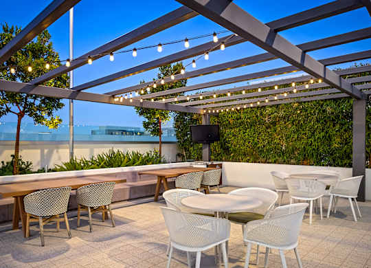 Rooftop patio with string lights and dining tables at Elements Apartments, California