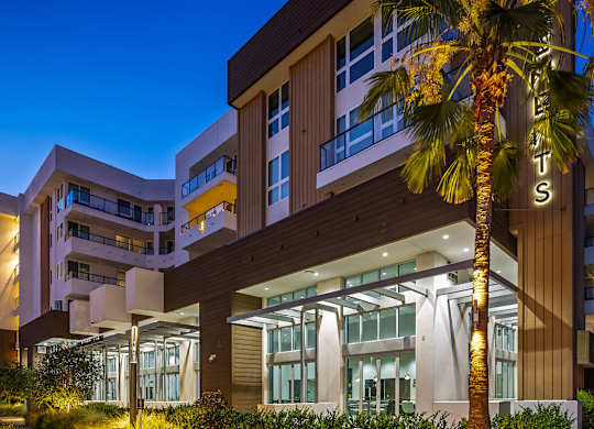 Modern building entrance with illuminated palm tree at Elements Apartments, Irvine, CA