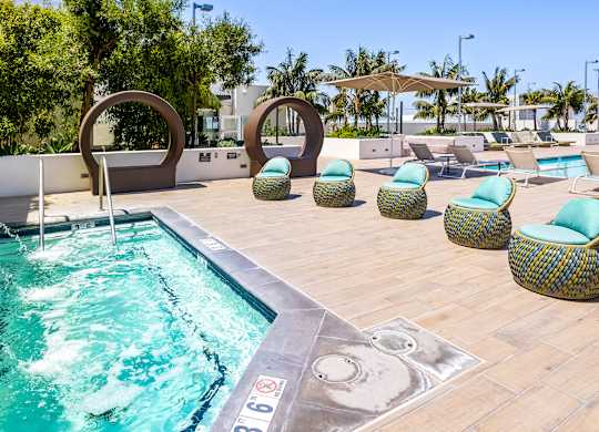 Spa with decorative sculptures and woven lounge chairs at Elements Apartments, Irvine