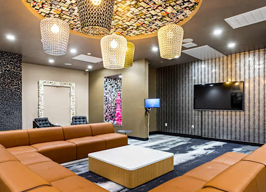 Resident lounge with woven pendant lights and brown sectionals at Elements Apartments, Irvine
