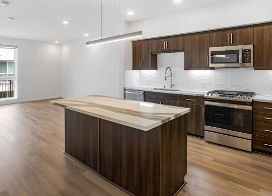 Modern kitchen with island and wood cabinetry at Elements Apartments, California, 92612