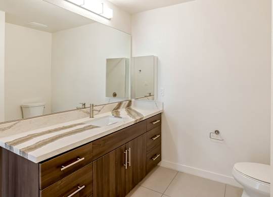 Bathroom with wood vanity and modern countertop at Elements Apartments, Irvine